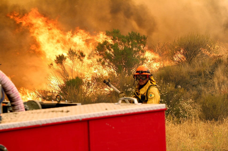 Los Angeles County firefighters pause to fight the flames due to erratic winds in Placenta Caynon Road in Santa Clarita, Calif., Sunday, July 24, 2016. Flames raced down a steep hillside "like a freight train," leaving smoldering remains of homes and warnings that more communities should be ready to flee the wildfire churning through tinder-dry canyons in Southern California, authorities said Sunday. (AP Photo/Matt Hartman)