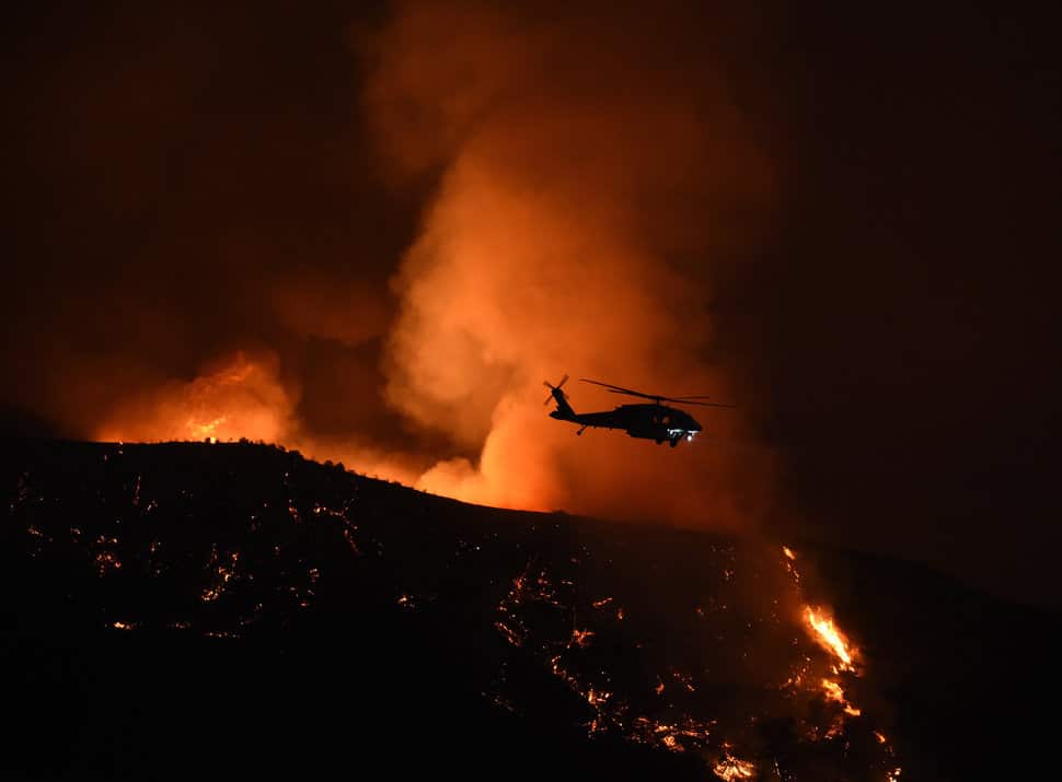 A firefighting helicopter makes a drop at Fair Oaks Canyon during the Sand Fire in Santa Clarita, California on July 24, 2016. Triple-digit temperatures and dry conditions are fueling the wildfire, which has burned across at least 22,000 acres so far and is only 10 percent contained. / AFP / Mark Ralston (Photo credit should read MARK RALSTON/AFP/Getty Images)