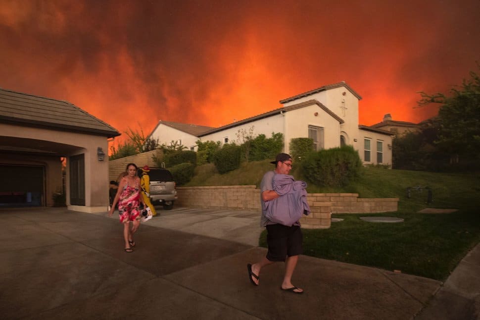 TOPSHOT - Residents flee their home as flames from the Sand Fire close in on July 23 2016 near Santa Clarita, California. Fueled by temperatures reaching about 108 degrees fahrenheit, the wildfire began yesterday has grown to 11,000 acres. / AFP / DAVID MCNEW (Photo credit should read DAVID MCNEW/AFP/Getty Images)