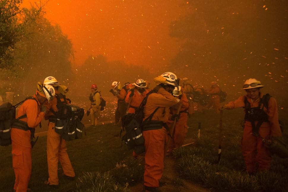 Inmate handcrew firefighters shield themselves from embers and heavy smoke as flames close in on houses at the Sand Fire on July 23 2016 near Santa Clarita, California. Fueled by temperatures reaching about 108 degrees fahrenheit, the wildfire began yesterday has grown to 11,000 acres. / AFP / DAVID MCNEW (Photo credit should read DAVID MCNEW/AFP/Getty Images)
