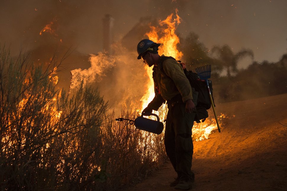 A firefighter with the Texas Canyon Hotshot crew lights a backfire near homes to fight the Sand Fire on July 23 2016 near Santa Clarita, California. Fueled by temperatures reaching about 108 degrees fahrenheit, the wildfire began yesterday has grown to 11,000 acres. / AFP / DAVID MCNEW (Photo credit should read DAVID MCNEW/AFP/Getty Images)