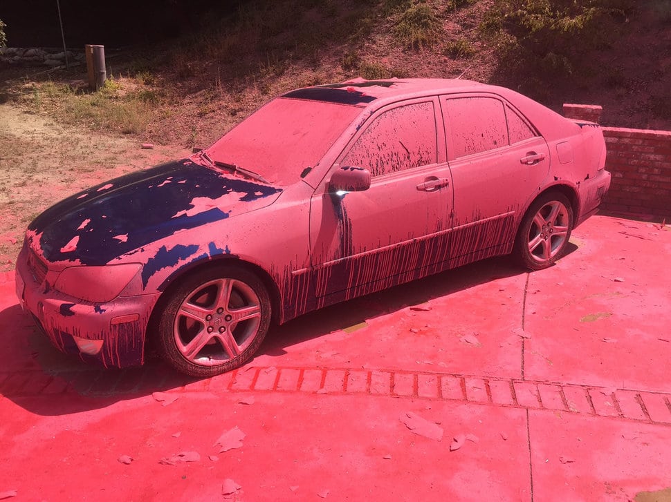 A car covered in aerially-applied fire retardant remains parked in Ruthspring Dr., in Santa Clarita, Calif., on Sunday, July 24, 2016. Two massive wildfires raged in tinder-dry California hills and canyons Sunday, leaving thousands of homes evacuated and authorities to investigate a burned body found in a neighborhood swept by flames. Firefighters have been trying to beat back a fire since Friday that has blackened more than 34 square miles of brush on ridgelines near the city of Santa Clarita and the Angeles National Forest. (AP Photo/Matt Hartman)