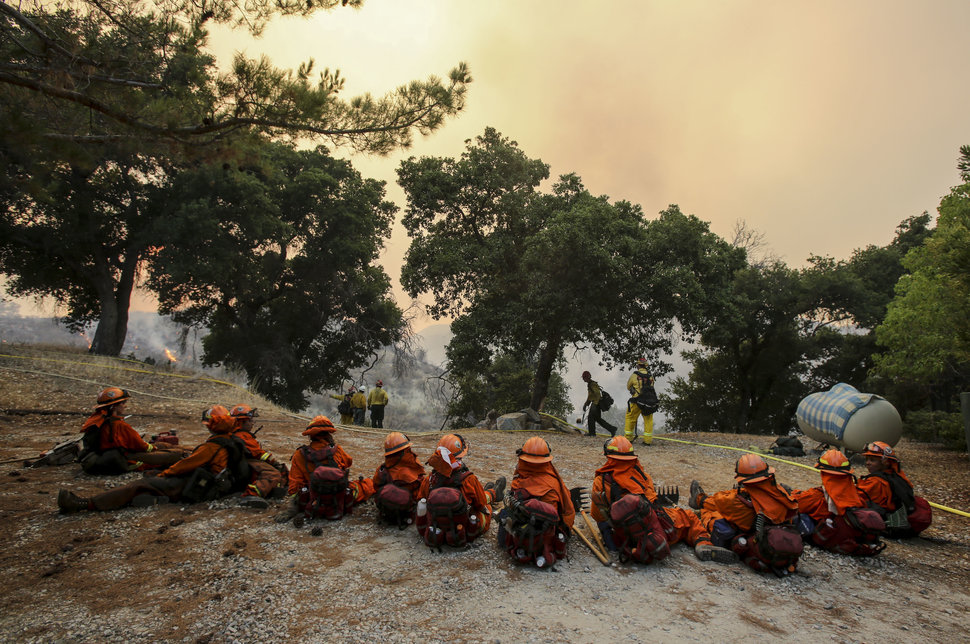 Members of hand crew rest on a hillside near Placenta Canyon Road as a wildfire burns in Santa Clarita, Calif., Sunday, July 24, 2016. Thousands of homes remained evacuated Sunday as two massive wildfires raged in tinder-dry California hills and canyons. (AP Photo/Ringo H.W. Chiu)